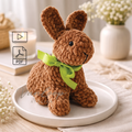 Brown plush baby bunny crochet pattern with video and PDF icons, lime bow, and craft background