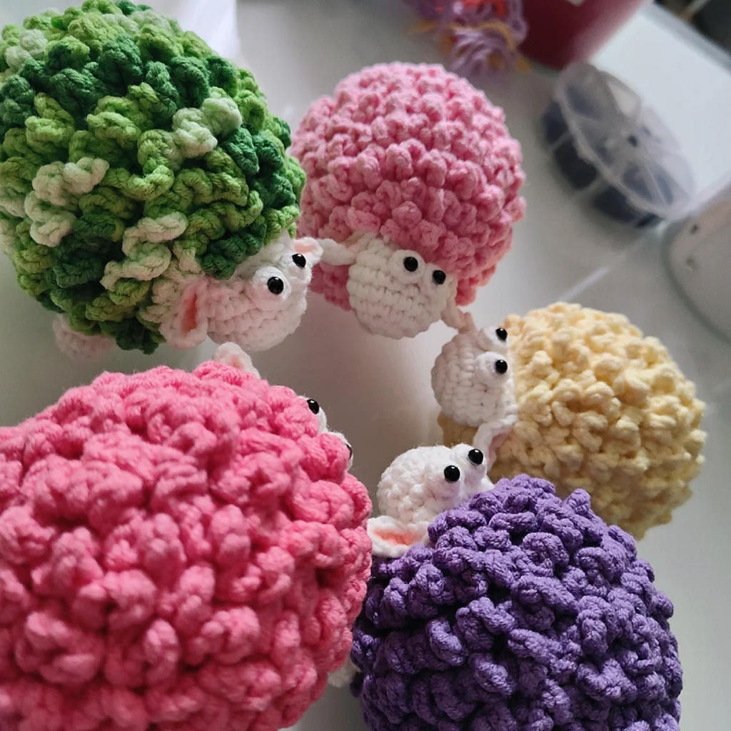 Five fluffy sheep amigurumi crochet color variations in green pink yellow and purple
