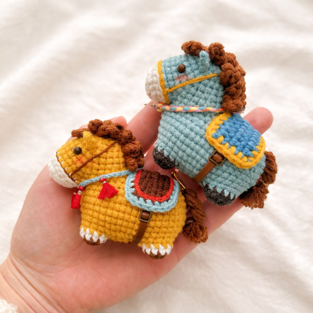 Yellow and turquoise miniature crochet horses wearing embroidered colorful saddles and bridles