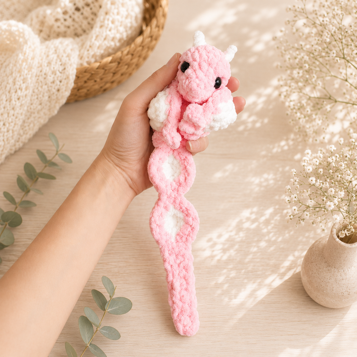 Pink interactive crochet dragon shown full-length with extended tail